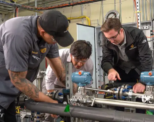 Three employees working on a piece of equipment