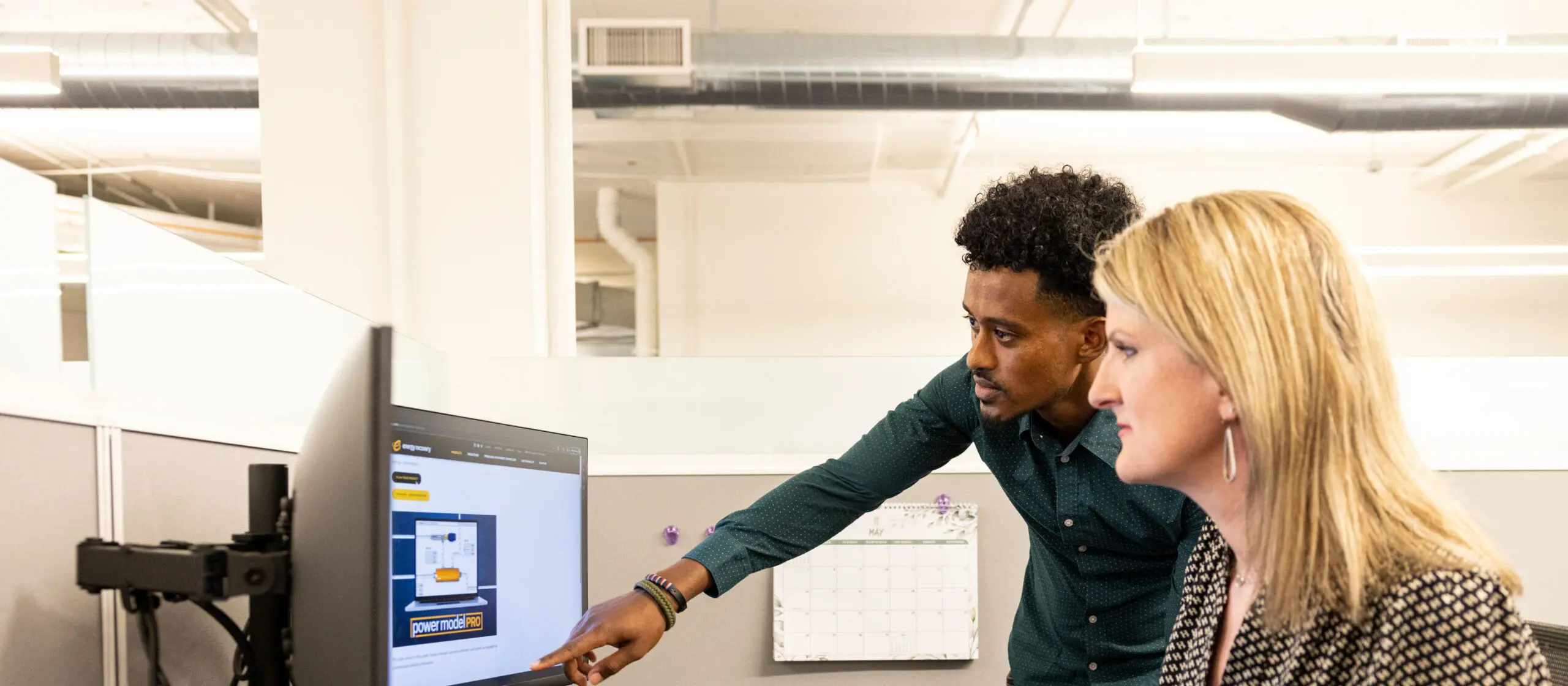 Two coworkers reviewing content on a desktop monitor