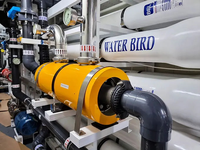 Industrial water treatment system with large white tanks labeled “WATER BIRD,” connected pipes, gauges, and a yellow cylindrical filtration unit in the foreground.
