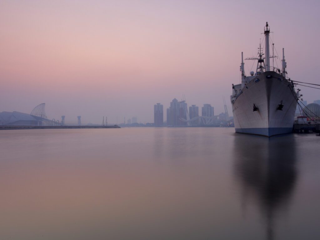 A large ship in a body of water with a skyline behind it
