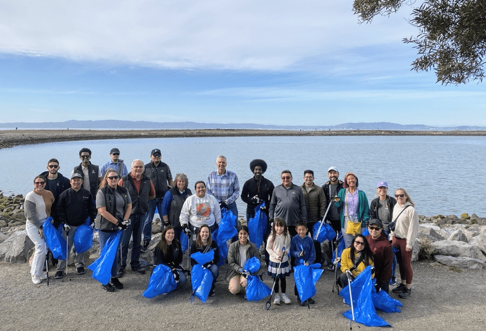 A group of employees holding trash bags next to a body of water