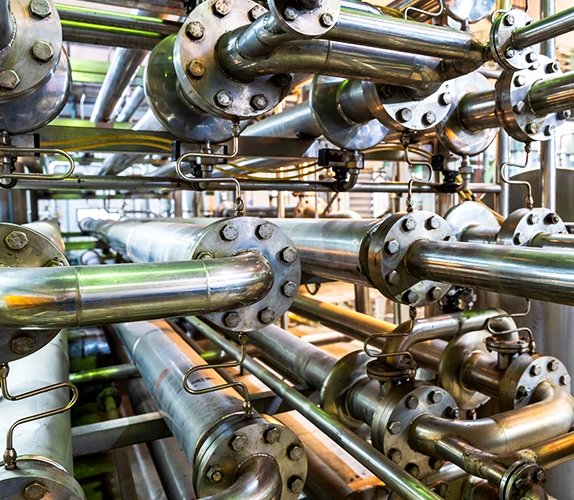 Close-up view of interconnected stainless steel industrial pipes and valves inside a chemical processing facility.