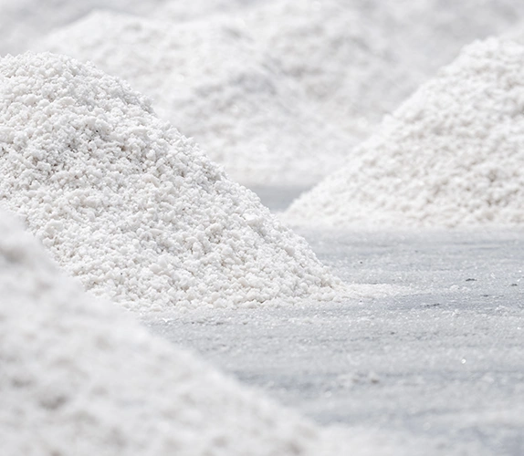 Mounds of harvested white salt on a flat industrial surface, highlighting crystalline texture and bulk material handling.